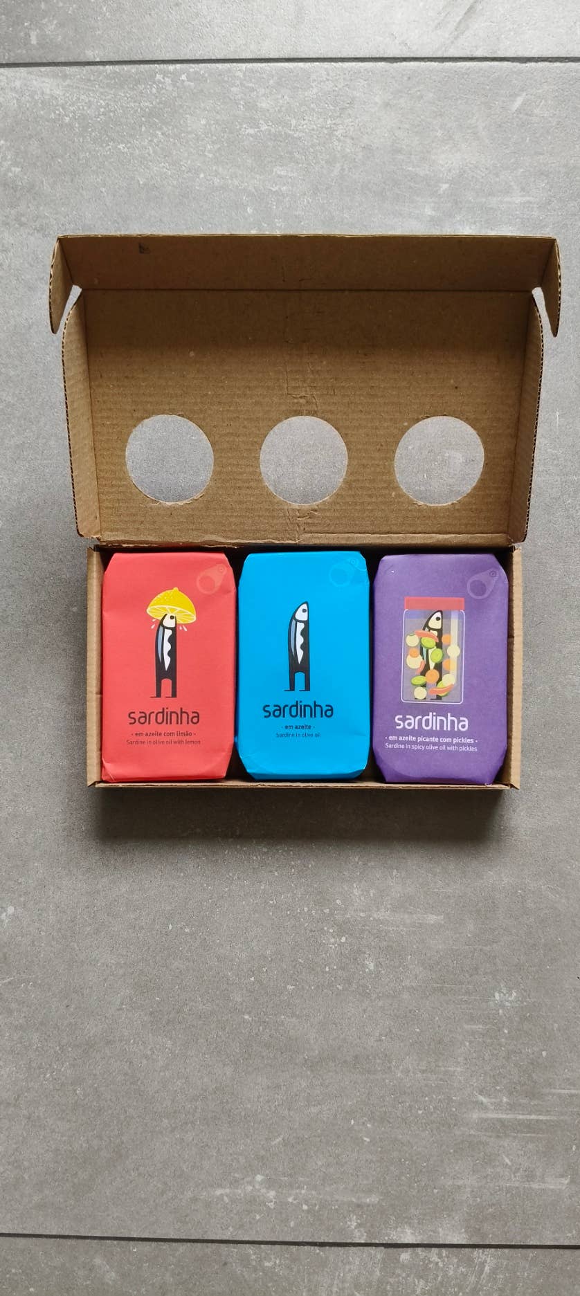 Open Sardinha gift box with red lemon, blue olive oil and purple spicy pickles sardine tins